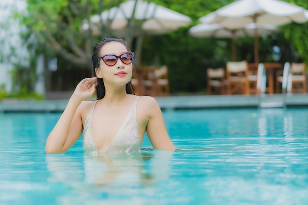 Foto gratuita retrato hermosa joven asiática relajarse sonrisa alrededor de la piscina al aire libre