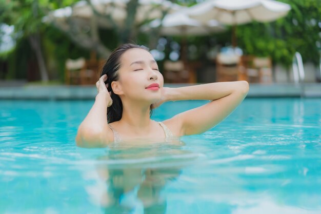 Retrato hermosa joven asiática relajarse sonrisa alrededor de la piscina al aire libre