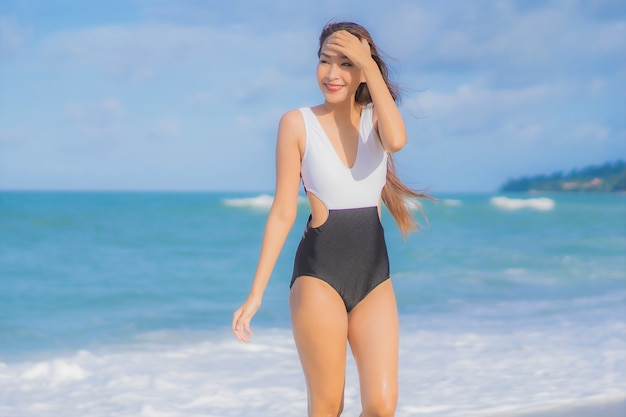 Retrato hermosa joven asiática relajarse sonrisa alrededor de la playa mar océano en vacaciones de vacaciones