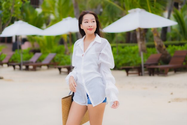 Retrato hermosa joven asiática relajarse sonrisa alrededor de la playa mar océano en viaje de vacaciones vacaciones