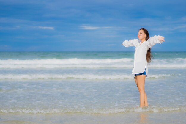 Retrato hermosa joven asiática relajarse sonrisa alrededor de la playa mar océano en viaje de vacaciones vacaciones