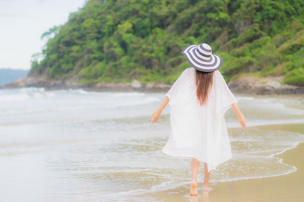 Retrato hermosa joven asiática relajarse sonrisa alrededor de la playa mar océano en viaje de vacaciones vacaciones