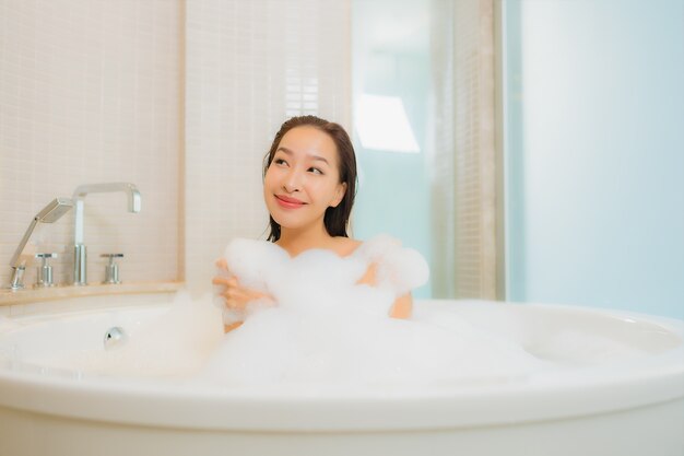 Retrato hermosa joven asiática relajarse sonrisa en la bañera en el interior del baño