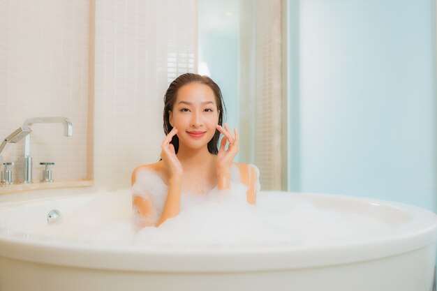 Retrato hermosa joven asiática relajarse sonrisa en la bañera en el interior del baño