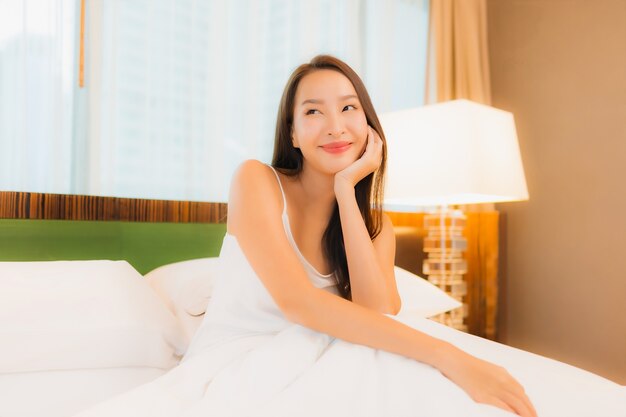 Retrato hermosa joven asiática relajarse sonrisa en la cama en el interior del dormitorio