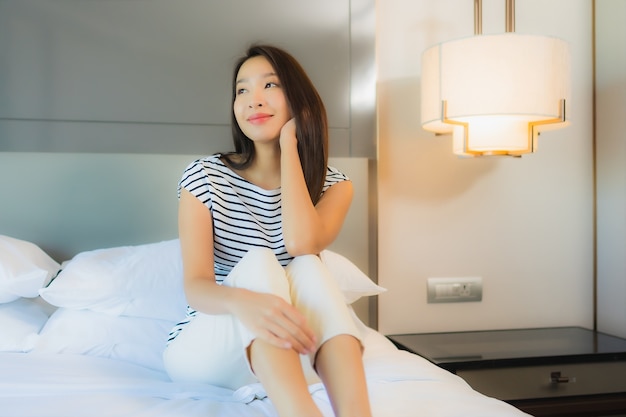 Retrato hermosa joven asiática relajarse sonrisa en la cama en el interior del dormitorio