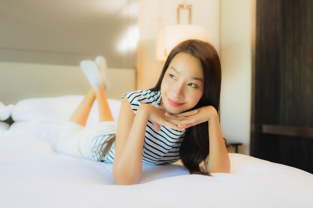 Retrato hermosa joven asiática relajarse sonrisa en la cama en el interior del dormitorio