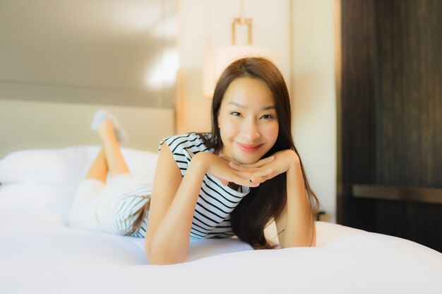 Retrato hermosa joven asiática relajarse sonrisa en la cama en el interior del dormitorio