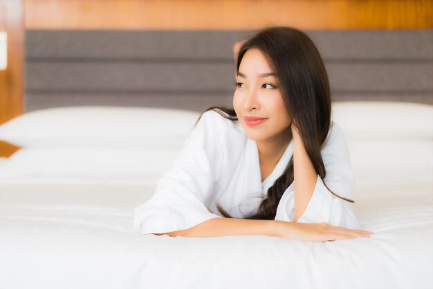 Retrato hermosa joven asiática relajarse sonrisa en la cama en el interior del dormitorio