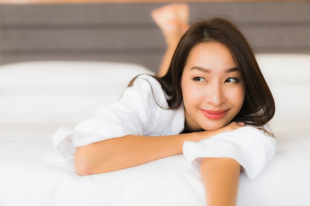 Retrato hermosa joven asiática relajarse sonrisa en la cama en el interior del dormitorio