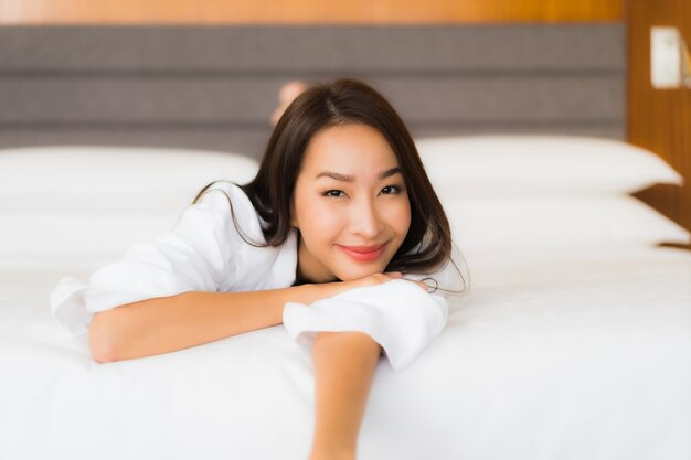 Retrato hermosa joven asiática relajarse sonrisa en la cama en el interior del dormitorio