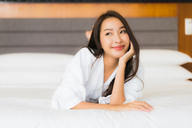 Retrato hermosa joven asiática relajarse sonrisa en la cama en el interior del dormitorio