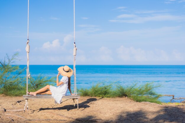 Retrato hermosa joven asiática relajarse sonrisa en columpio alrededor de la playa mar océano para viajes por la naturaleza en vacaciones