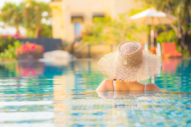 Retrato hermosa joven asiática relajarse sonrisa disfrutar de ocio alrededor de la piscina en el hotel resort de vacaciones