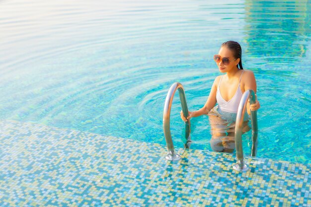 Retrato hermosa joven asiática relajarse sonrisa disfrutar de ocio alrededor de la piscina en el hotel resort de vacaciones