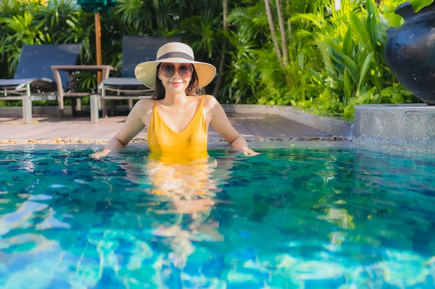 Retrato hermosa joven asiática relajarse sonrisa feliz alrededor de la piscina al aire libre en el hotel resort para vacaciones de ocio