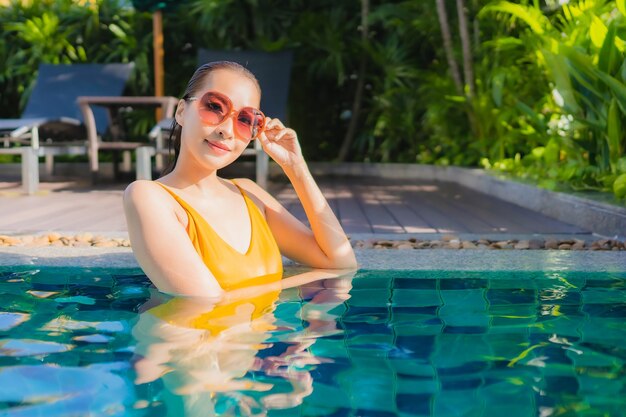 Retrato hermosa joven asiática relajarse sonrisa feliz alrededor de la piscina al aire libre en el hotel resort para vacaciones de ocio