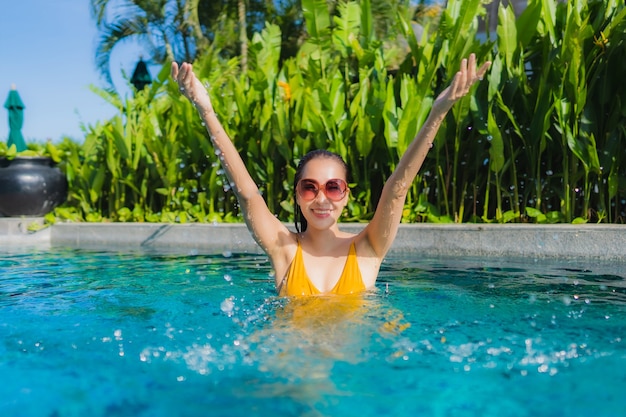 Retrato hermosa joven asiática relajarse sonrisa feliz alrededor de la piscina al aire libre en el hotel resort para vacaciones de ocio