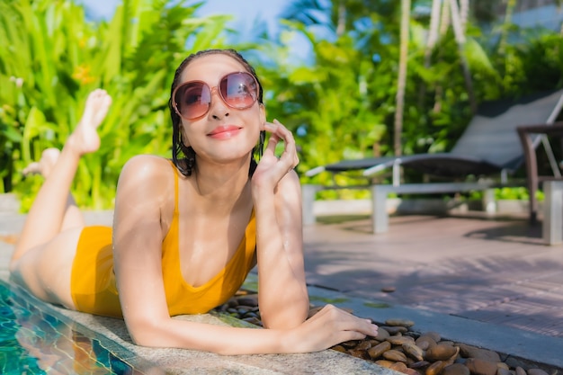Retrato hermosa joven asiática relajarse sonrisa feliz alrededor de la piscina al aire libre en el hotel resort para vacaciones de ocio