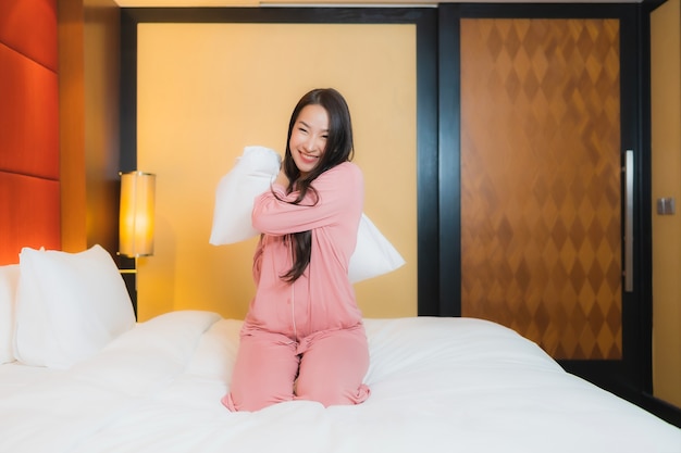 Foto gratuita retrato hermosa joven asiática relajarse sonrisa feliz en la cama en el interior del dormitorio