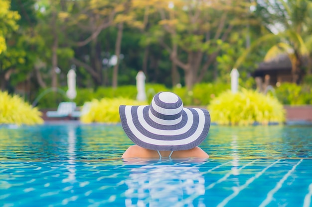 Retrato hermosa joven asiática relajarse sonrisa ocio alrededor de la piscina al aire libre cerca del mar