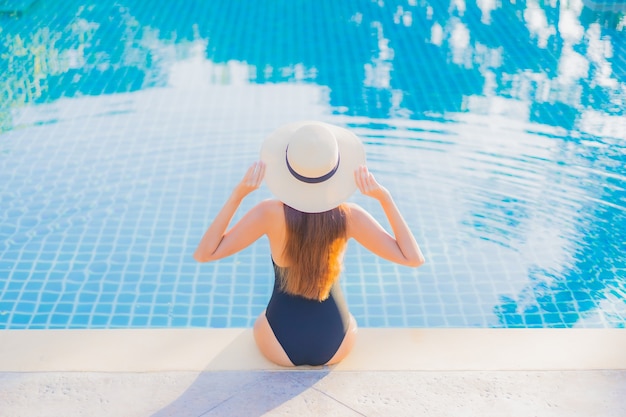 Foto gratuita retrato hermosa joven asiática relajarse sonrisa ocio alrededor de la piscina al aire libre cerca del mar