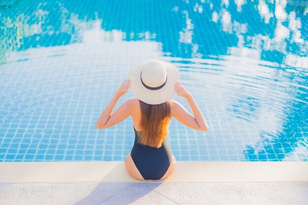 Retrato hermosa joven asiática relajarse sonrisa ocio alrededor de la piscina al aire libre cerca del mar