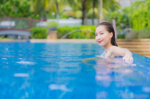 Retrato hermosa joven asiática relajarse sonrisa ocio alrededor de la piscina al aire libre en el hotel resort en viajes de vacaciones