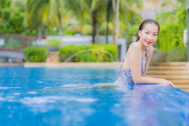 Retrato hermosa joven asiática relajarse sonrisa ocio alrededor de la piscina al aire libre en el hotel resort en viajes de vacaciones