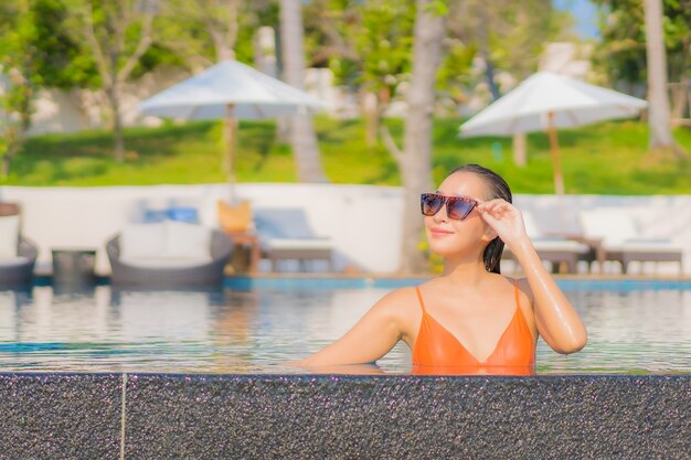 Retrato hermosa joven asiática relajarse sonrisa ocio alrededor de la piscina al aire libre en el hotel resort con vista al mar