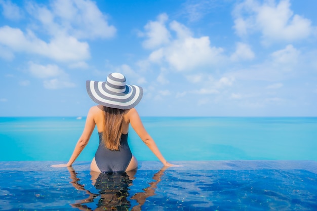 Retrato hermosa joven asiática relajarse sonrisa ocio alrededor de la piscina al aire libre en el hotel resort con vista al mar