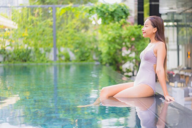 Retrato hermosa joven asiática relajarse sonrisa ocio alrededor de la piscina al aire libre en el hotel resort