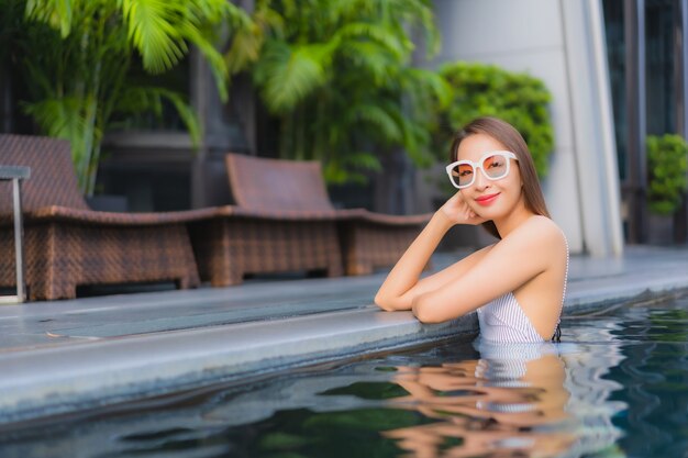 Retrato hermosa joven asiática relajarse sonrisa ocio alrededor de la piscina al aire libre