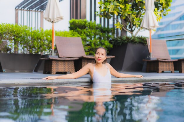 Retrato hermosa joven asiática relajarse sonrisa ocio alrededor de la piscina al aire libre