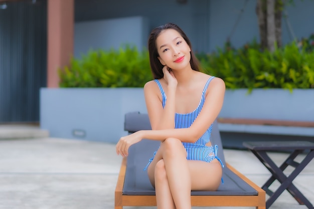 Retrato hermosa joven asiática relajarse sonrisa ocio alrededor de la piscina al aire libre