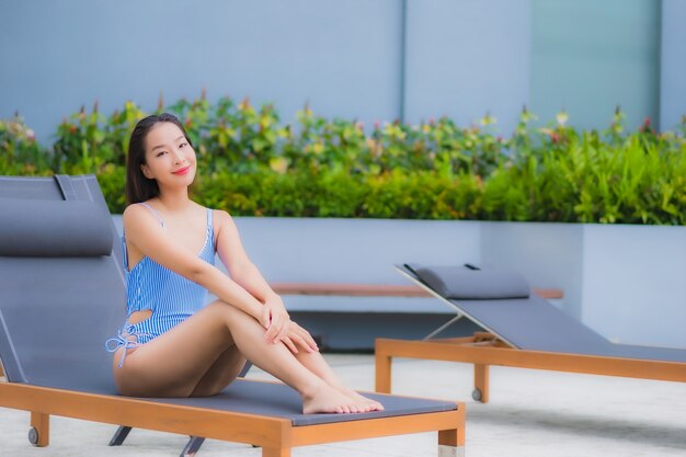 Retrato hermosa joven asiática relajarse sonrisa ocio alrededor de la piscina al aire libre