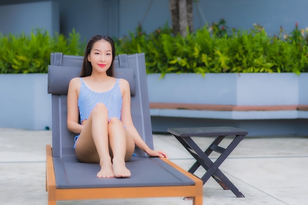 Retrato hermosa joven asiática relajarse sonrisa ocio alrededor de la piscina al aire libre