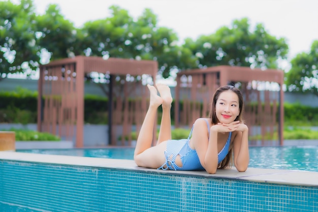 Retrato hermosa joven asiática relajarse sonrisa ocio alrededor de la piscina al aire libre