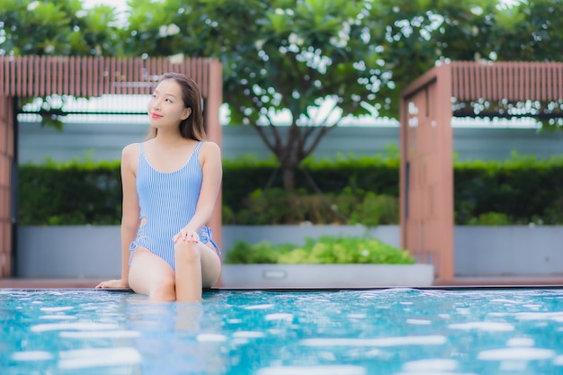 Retrato hermosa joven asiática relajarse sonrisa ocio alrededor de la piscina al aire libre