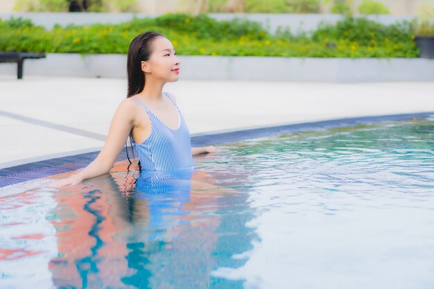 Retrato hermosa joven asiática relajarse sonrisa ocio alrededor de la piscina al aire libre