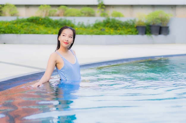 Retrato hermosa joven asiática relajarse sonrisa ocio alrededor de la piscina al aire libre