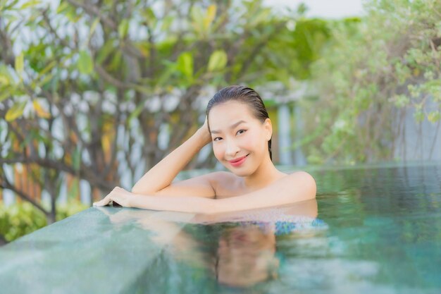 Retrato hermosa joven asiática relajarse sonrisa ocio alrededor de la piscina al aire libre