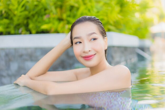 Retrato hermosa joven asiática relajarse sonrisa ocio alrededor de la piscina al aire libre