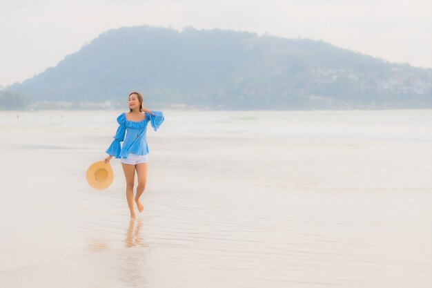 Retrato hermosa joven asiática relajarse sonrisa de ocio alrededor de la playa mar océano al atardecer