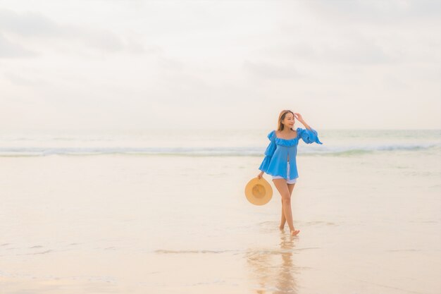 Retrato hermosa joven asiática relajarse sonrisa de ocio alrededor de la playa mar océano al atardecer