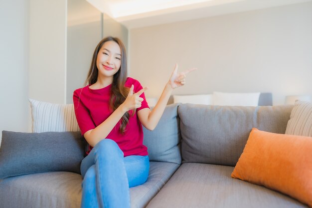 Retrato hermosa joven asiática relajarse sonrisa en el sofá en el salón