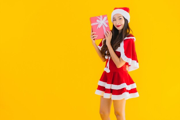 Retrato hermosa joven asiática ropa de navidad y sombrero sonríen feliz con caja de regalo roja