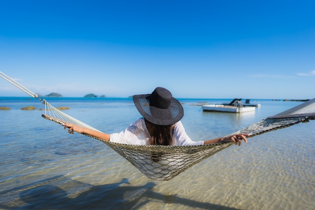 Retrato hermosa joven asiática sentada en una hamaca alrededor del mar playa océano para relajarse