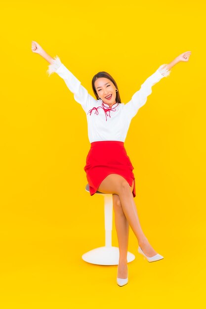 Retrato hermosa joven asiática sentarse en una silla en amarillo