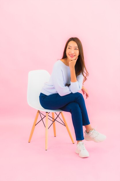 Retrato hermosa joven asiática sentarse en una silla con pared de color rosa